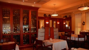 A restaurant interior with multiple tables, chairs, and a wine display. - Hôtel Mingan (Sept-Iles)