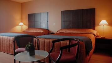 A hotel room with two beds, a small table, and two chairs.