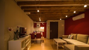 Una sala de estar moderna con un sofá, un televisor y un comedor con sillas y una mesa.