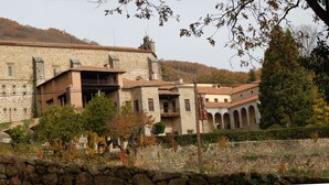 Un edificio de piedra con un patio interior, rodeado de árboles y colinas.