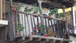 Un balcón rústico con barandillas de madera y plantas en macetas.