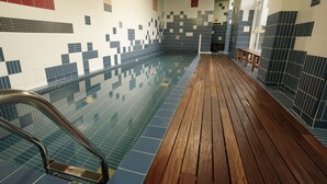 Piscina con paredes de azulejos y terraza de madera.