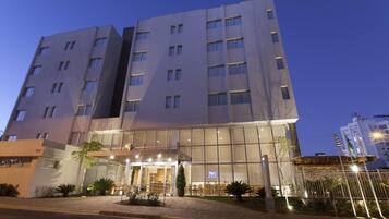 A modern hotel with a glass facade, multiple floors, and a well-lit entrance.