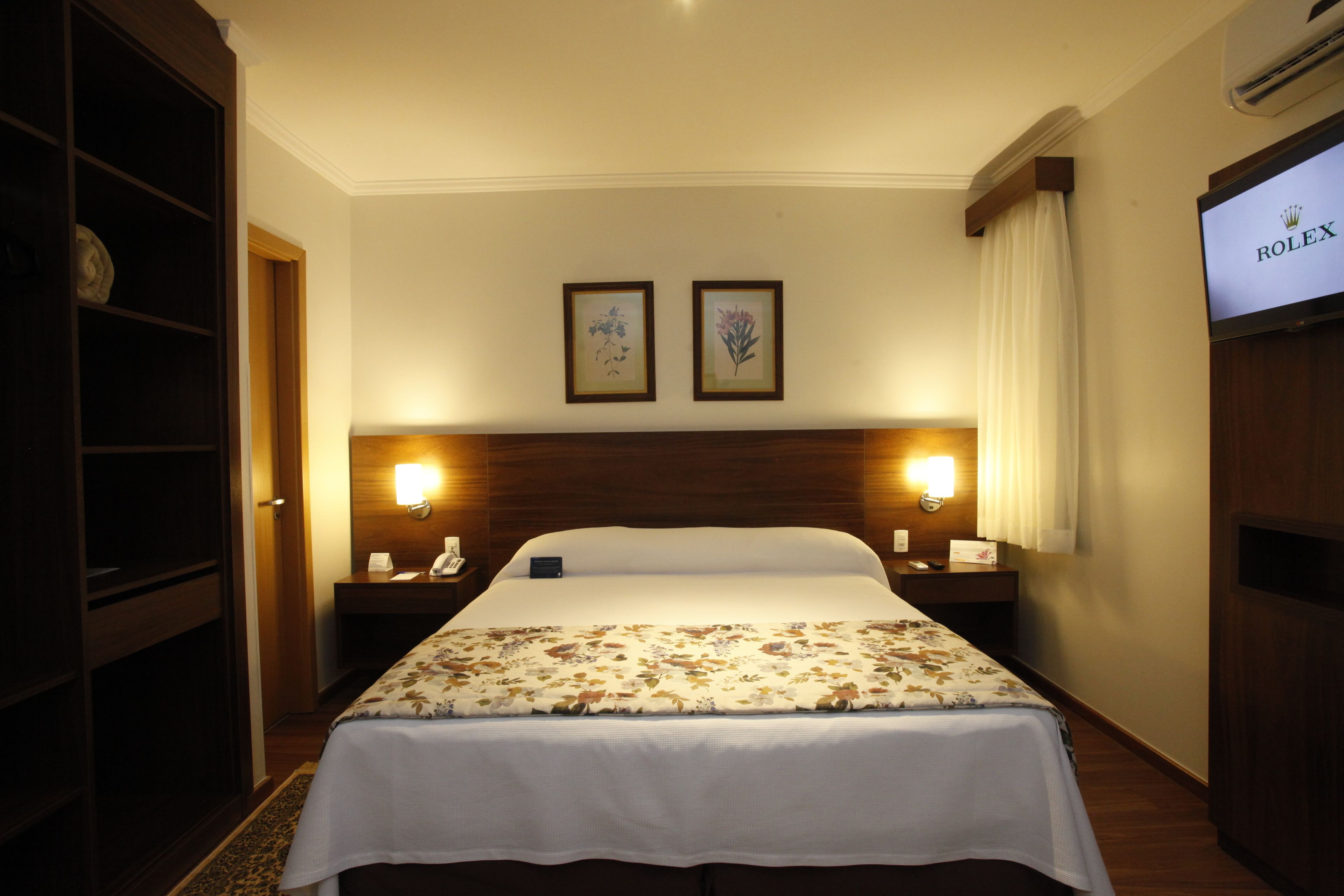 Une chambre d’hôtel avec un grand lit, deux lampes de chevet, une télévision et une armoire.
