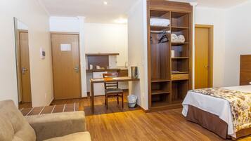 A bedroom with a bed, a wooden wardrobe, a desk, and a chair.