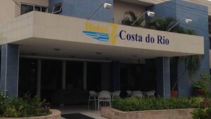 The exterior of Hotel Costa do Rio with a covered entrance, outdoor seating area, and wheelchair accessibility sign. - Costa do Rio Hotel (Petrolina)
