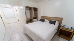 A bedroom with a large bed, a wardrobe, a bedside table, and a small desk. - Costa do Rio Hotel (Petrolina)