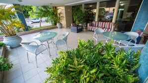 A hotel lobby with a seating area, potted plants, and a view of the street. - Costa do Rio Hotel (Petrolina)