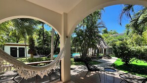 Un espacio al aire libre cubierto con una hamaca, sillas y una piscina.