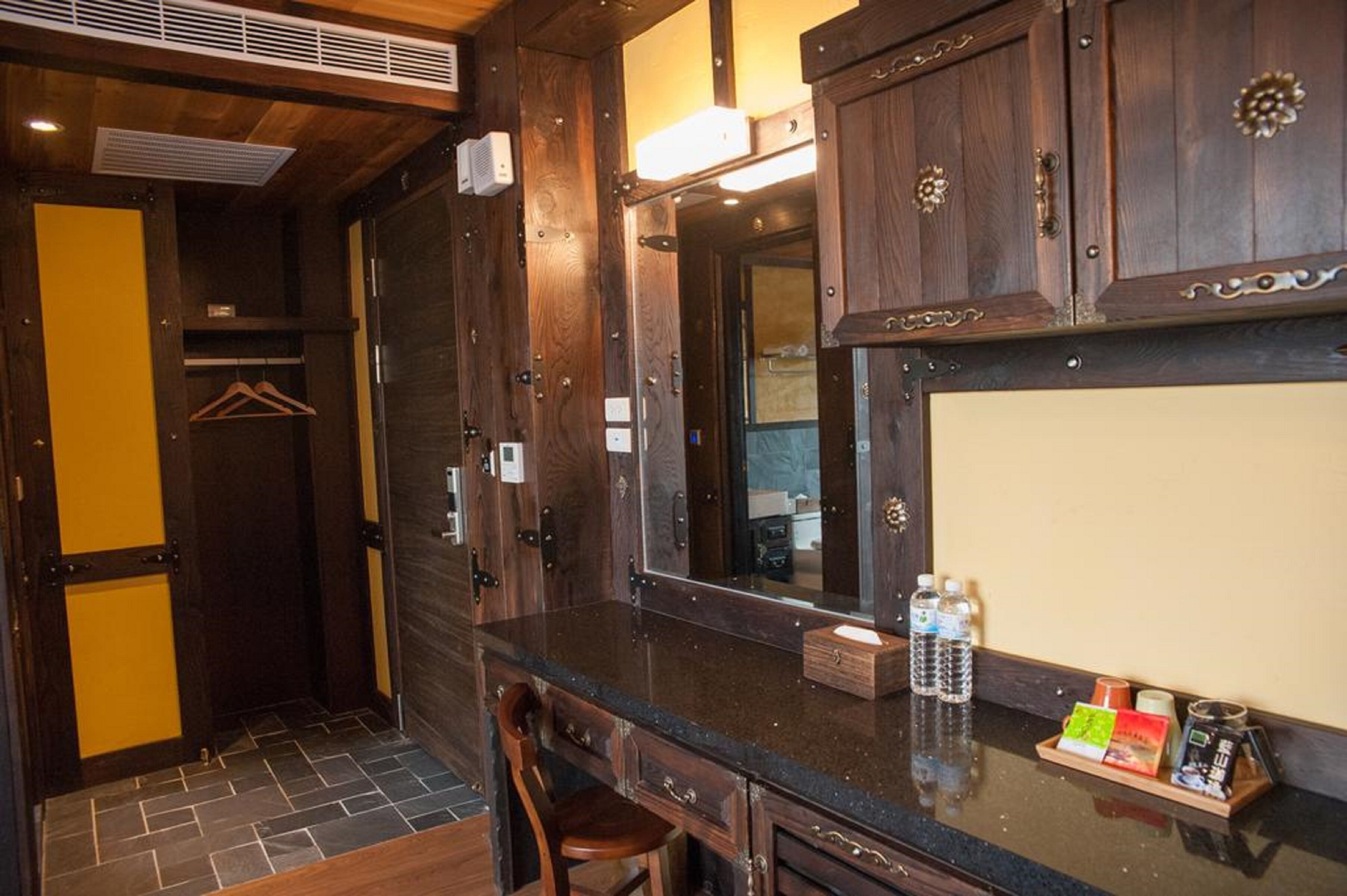 Une salle de bain avec des meubles en bois, un miroir, un lavabo avec un plan de travail et une chaise.