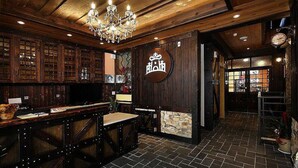 A bar area with wooden walls, a chandelier, and a clock.