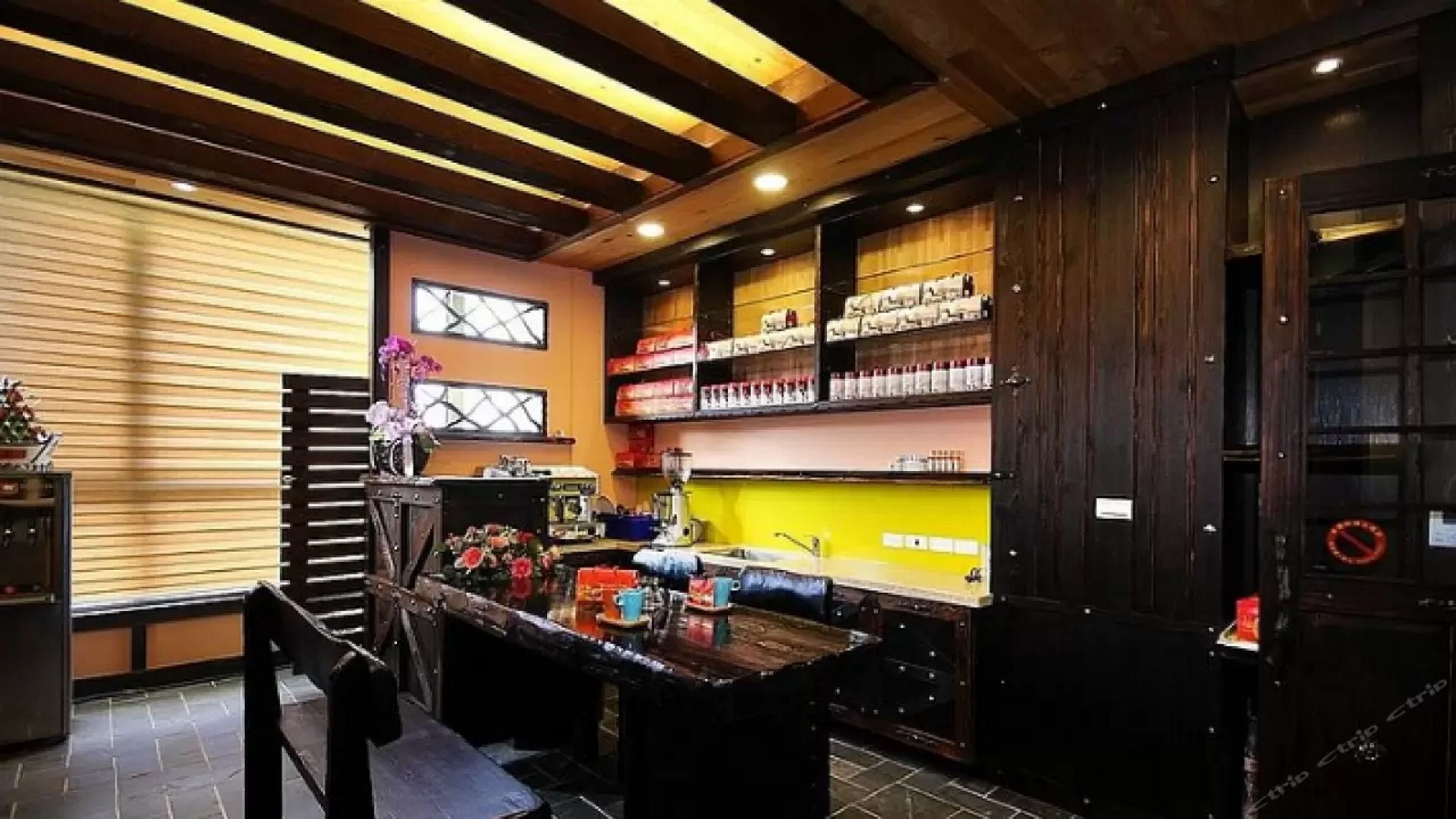 A kitchen with wooden beams, a central island, and shelves stocked with kitchen items.
