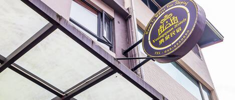 Et hotelskilt med kinesiske tegn og et telefonnummer.