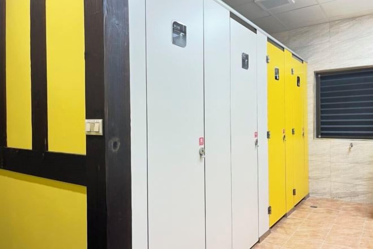Una fila de taquillas con una combinación de colores amarillo y blanco, suelo de baldosas y una puerta de garaje cerrada al fondo.