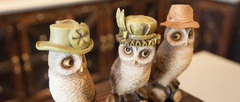 Tres figuras de búhos con sombreros sobre una superficie de madera.