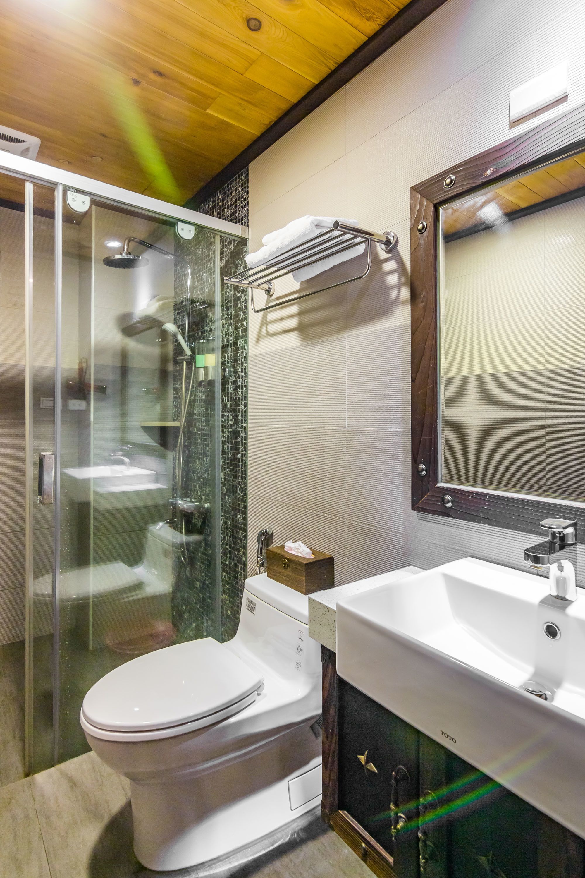 A modern bathroom with a glass-enclosed shower, a white toilet, and a vanity with a sink and mirror.