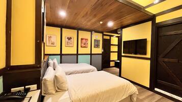 A hotel room with two beds, a desk with a telephone, and artwork on the walls.