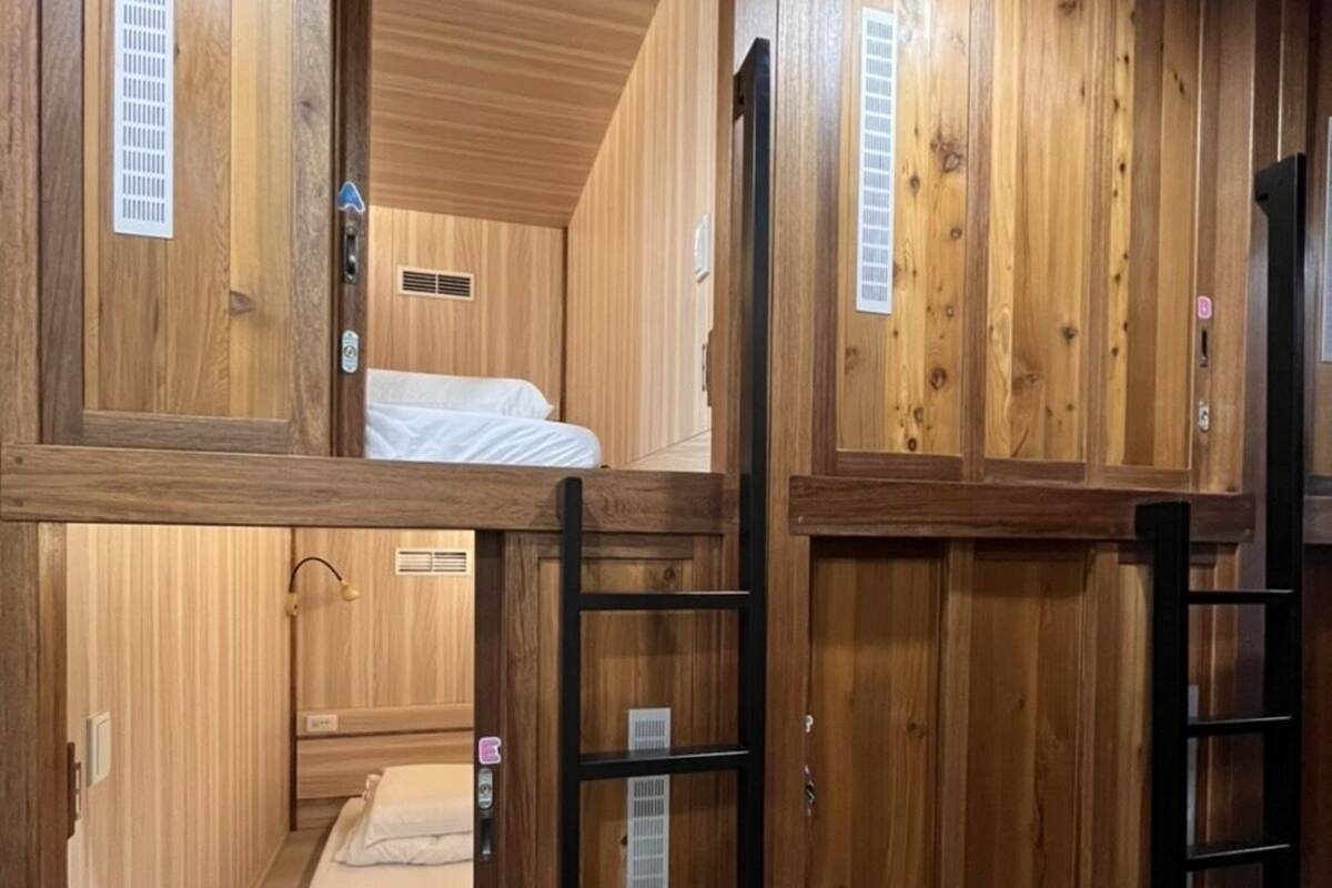 Una habitación de madera con literas, una escalera y un ventanal pequeño.