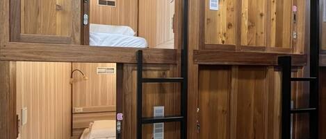 A wooden room with bunk beds, a ladder, and a small window.