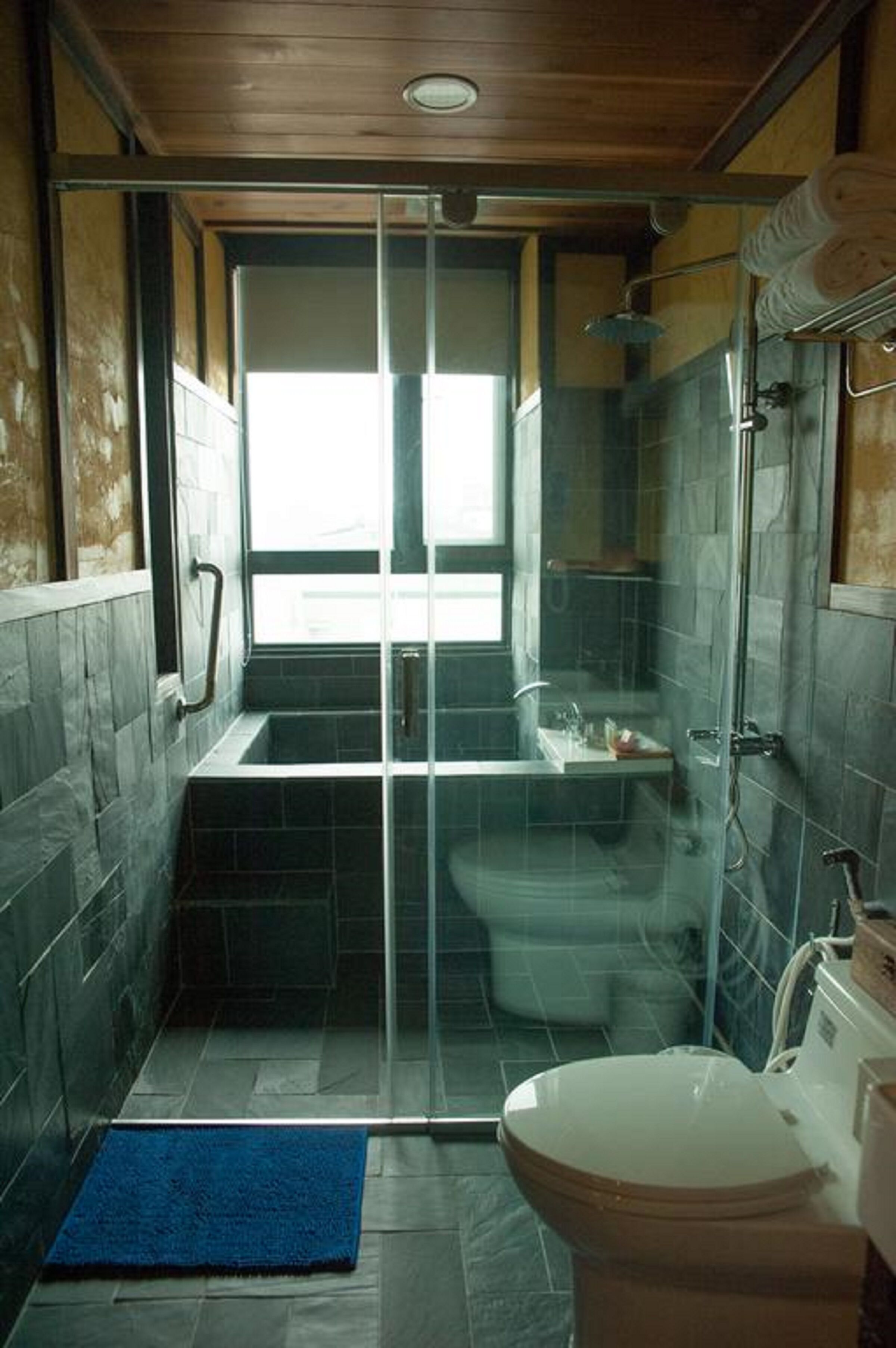 A bathroom with a glass-enclosed shower, a bathtub, and a toilet.