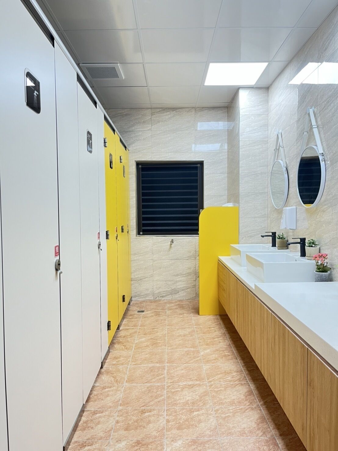 A modern bathroom with white lockers, a yellow cabinet, and a vanity with two sinks.