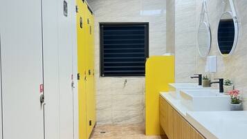 A modern bathroom with white lockers, a yellow cabinet, and a vanity with two sinks.