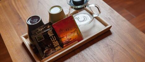 A tray with a coffee maker, a glass of milk, and a book on a wooden table.