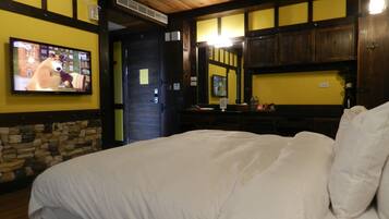Una habitación de hotel con una cama grande, un televisor montado en la pared y paneles de madera.