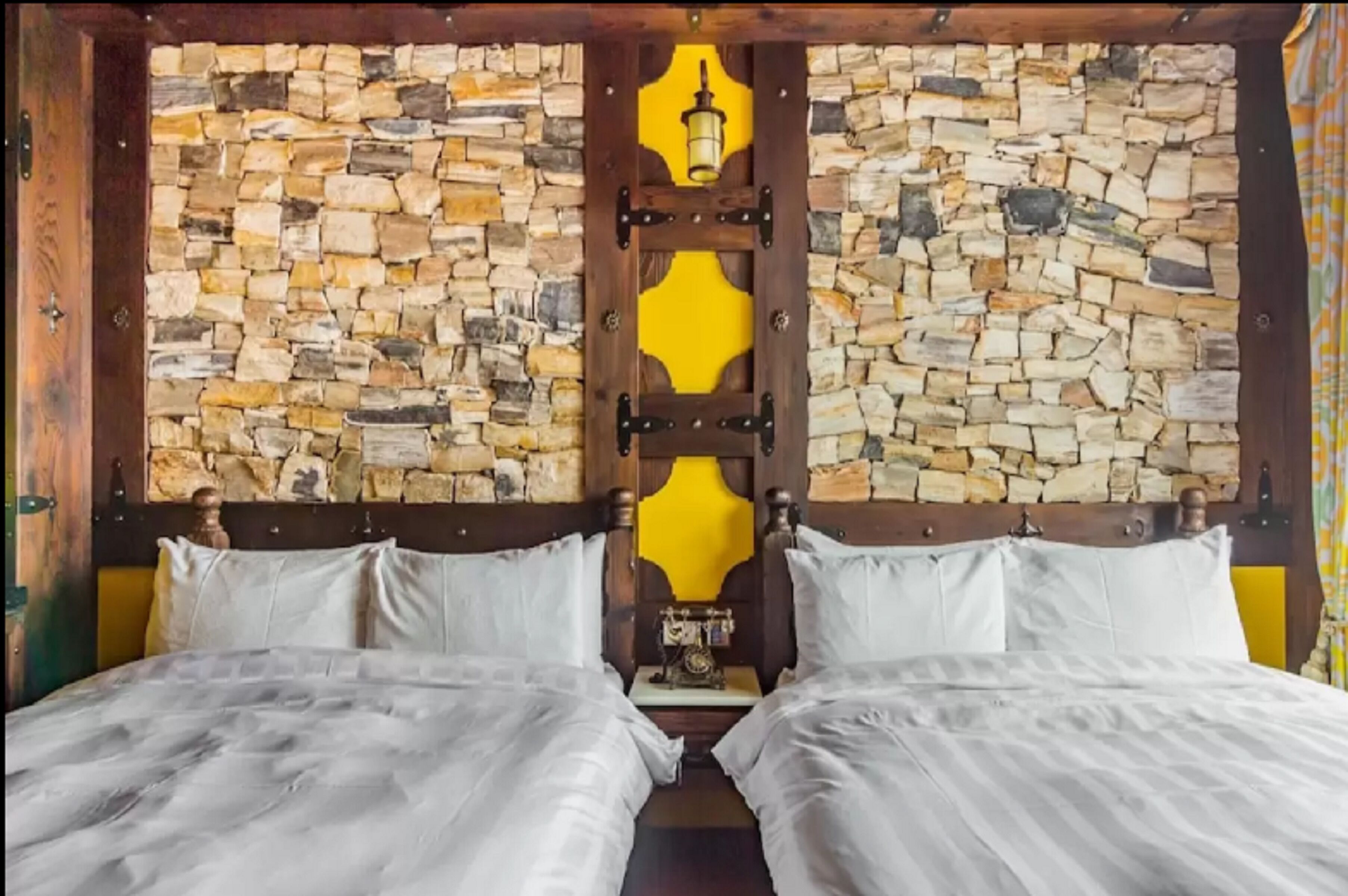 A room with a stone wall and a wooden bed frame.