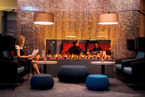 A modern lounge area with seating, a fire feature, and a decorative wall. - Holiday Inn Express Karlsruhe - City Park by IHG (Karlsruhe)