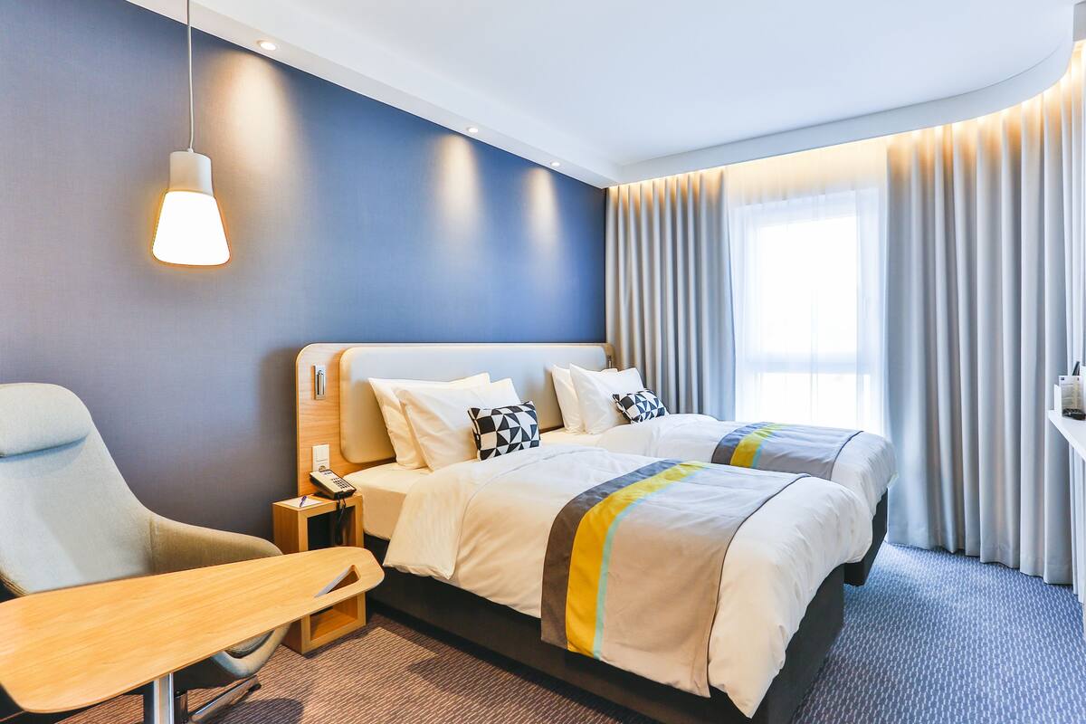 Une chambre d’hôtel avec un grand lit, un bureau, une chaise et un téléviseur.