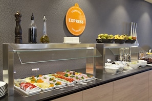 Un bufé con diferentes opciones de comida, incluyendo carnes, quesos y frutas.