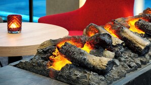 A fire feature with logs and a candle on a table.