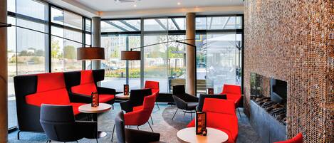 A modern interior with red and black seating, large windows, and a textured wall feature.