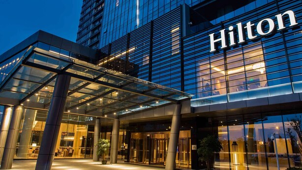 A modern hotel entrance with a glass facade and the name 'Hilton' prominently displayed.