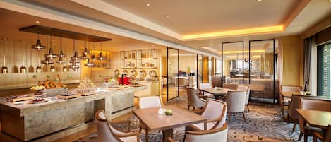 Een moderne hotellobby met een marmeren receptiebalie, een zithoek en uitzicht op de eetruimte.