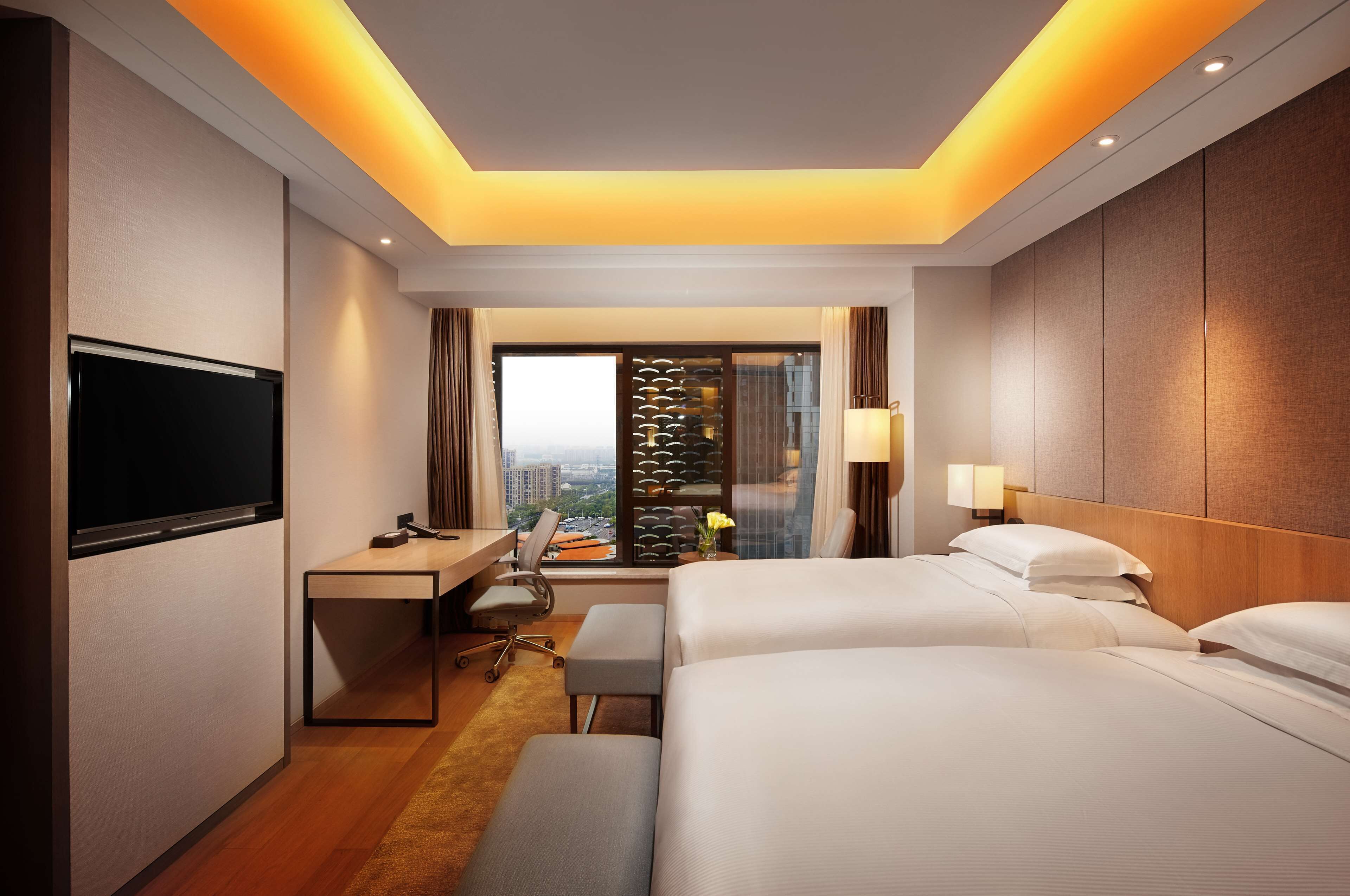 Camera d'albergo con un letto grande, una scrivania, una televisione e vista sulla città.