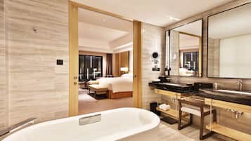 A modern hotel bathroom with a large bathtub, dual sinks, and a large mirror.