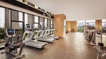 A modern gym with treadmills, weight machines, and a large window offering a city view.