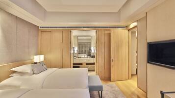 A modern hotel room with a large bed, a bench, a TV, a mirror, and a walk-in closet.