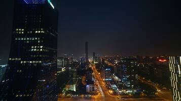 A nighttime cityscape with illuminated skyscrapers and a busy street.