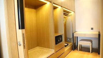A compact, well-lit room with a wooden wardrobe, a small bench, and a desk with a chair.