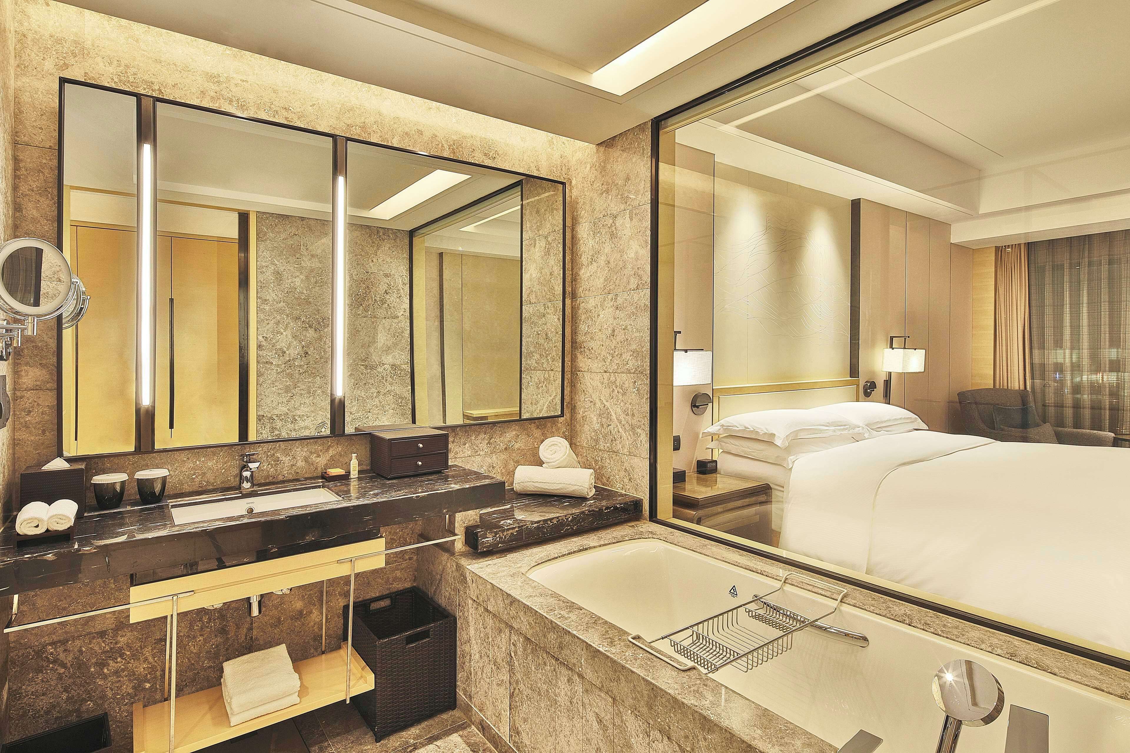 Un moderno baño de hotel con un espejo grande, una bañera, un lavabo y un mueble de tocador con toallas.
