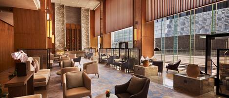 A spacious lobby with modern furnishings, large windows, and a high ceiling.