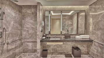 A modern bathroom with a large mirror, dual sinks, and a shower area.