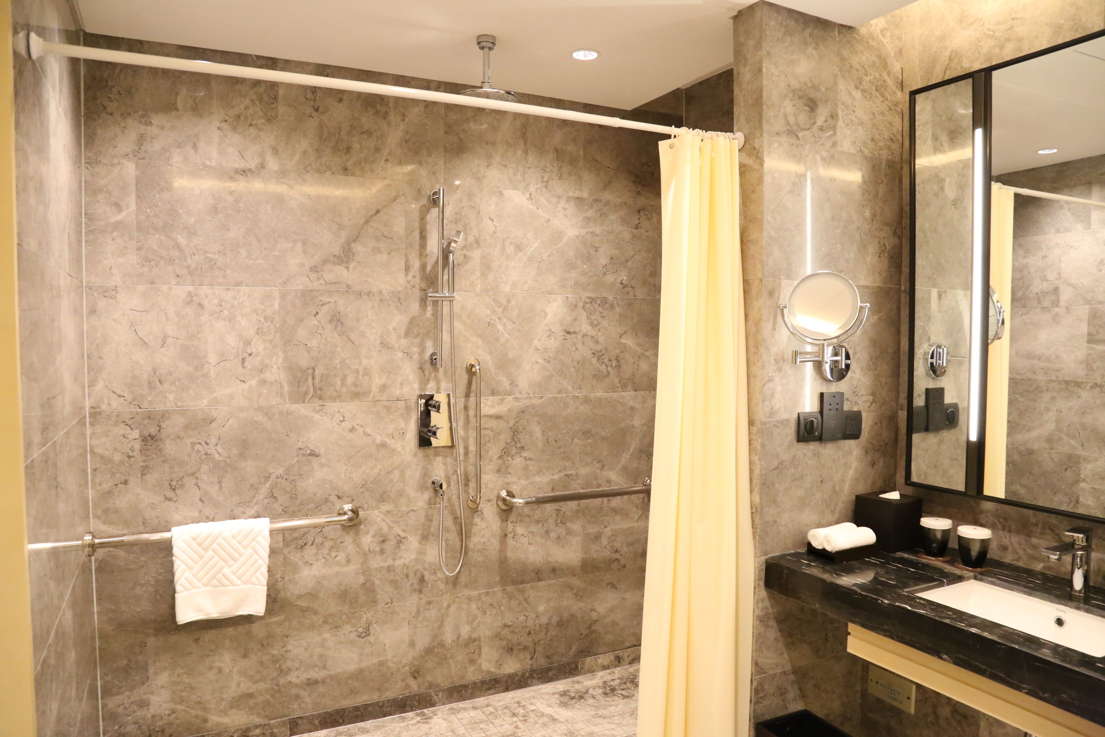 A modern bathroom with a shower, a vanity with a mirror, and a towel rack.