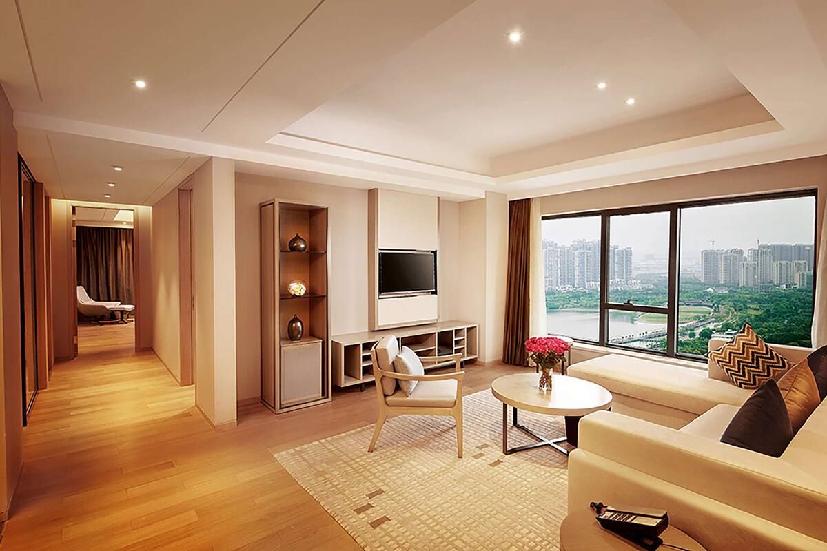 A modern living room with a sofa, TV, and a view of a cityscape.