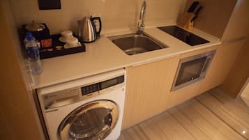 Una cocina compacta con lavadora, un lavamanos y un horno pequeño.