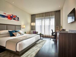 A hotel room with a large bed, a desk, a chair, and a television on the wall. - Vivanta Pune, Hinjawadi (Paud)