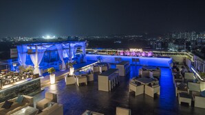A rooftop bar with outdoor seating, a city view, and a VANDAAAG sign.